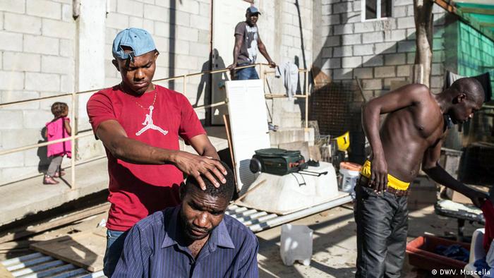 A Haitian man gives another Haitian a haircut at the Canyon of Scorpions, outside Tijuana, Mexico