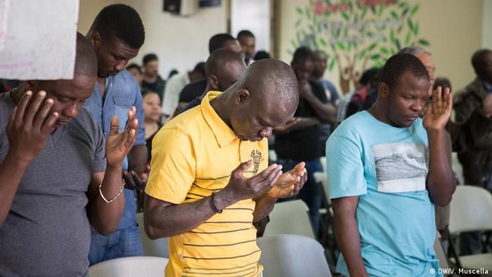 Haitian migrants pray during a mass at a shelter opened by Catholics