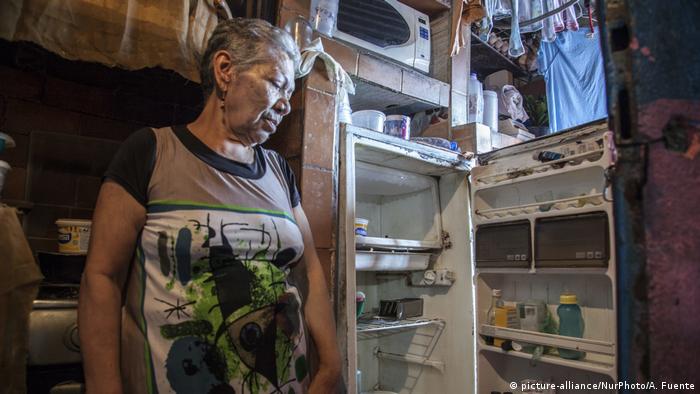 Una mujer en Caracas frente a un refrigerador casi vacío.