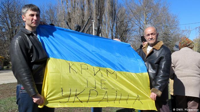 Жители Крыма держат флаг Украины с надписью Крым это Украина
